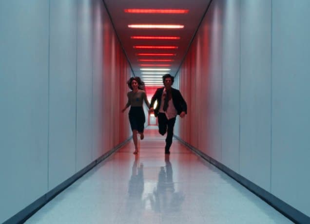 severance-season-3-theories: Two people run down a dimly lit hallway with red lights.