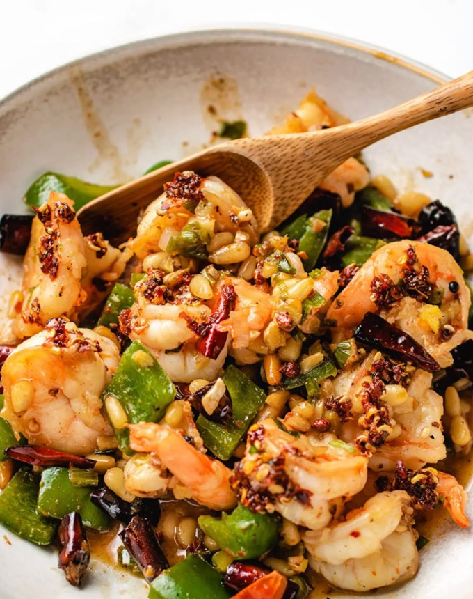 traditional chinese new year foods: kung pao shrimp in a bowl with a wooden spoon