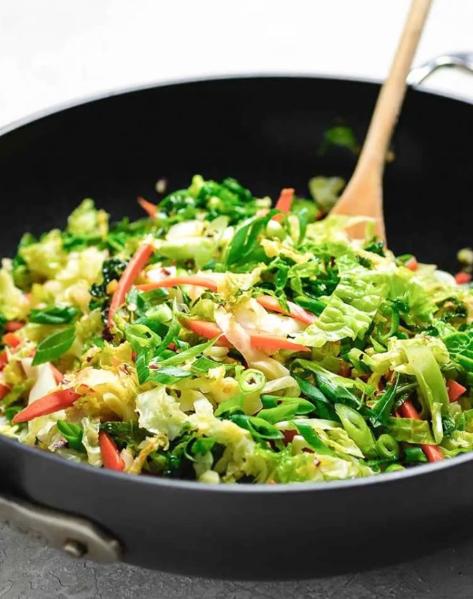 traditional chinese new year foods: vegetarian stir fry in a pan with a wooden spoon